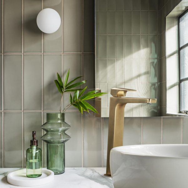 Magnifique salle de bains contemporaine de style art déco avec carrelage vertical vert, plan de toilette en marbre et détails en laiton.