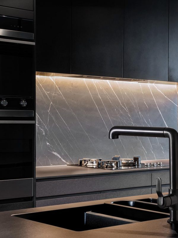 Contemporary dark styled kitchen with black marble splashback